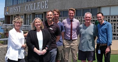 Former students and now Rosny Collage staff Cathy Ransom, Clare Latham, Gav Joyce, Callum Hollingsworth, Andrew Woodham, Ray Riewoldt and Tristan Ferguson standing in front of the Rosny Collage sign.