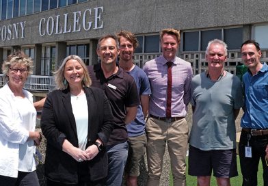 Former students and now Rosny Collage staff Cathy Ransom, Clare Latham, Gav Joyce, Callum Hollingsworth, Andrew Woodham, Ray Riewoldt and Tristan Ferguson standing in front of the Rosny Collage sign.